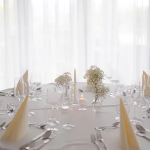 Elegantná výzdoba okrúhleho stola z gypsomilky so sviečkami vo vázach.